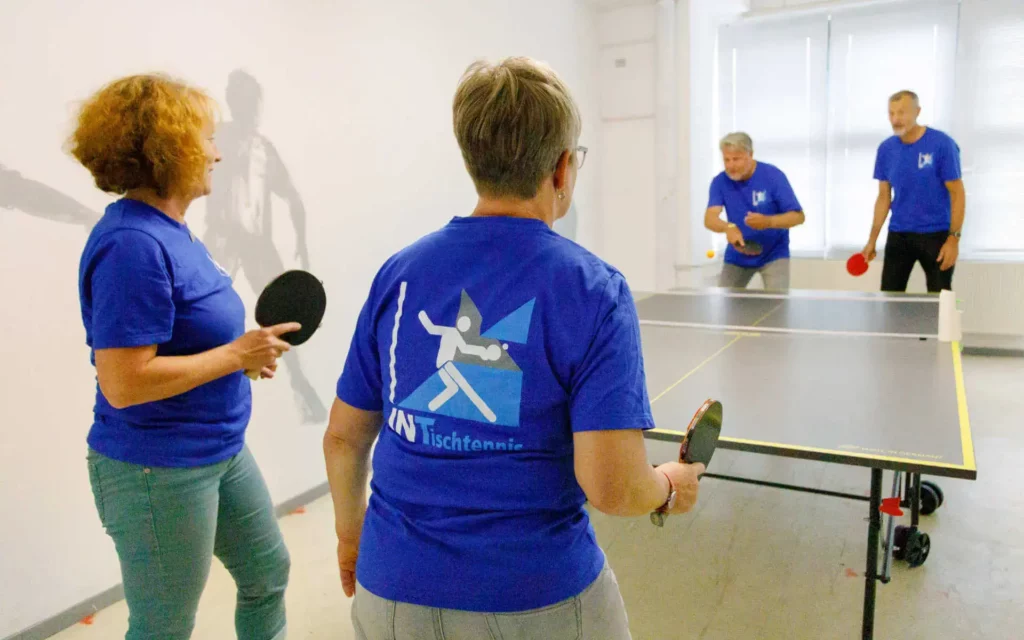 Mitarbeiter INT-BAU in blauen Shirts an Tischtennisplatte beim spielen | Benefits